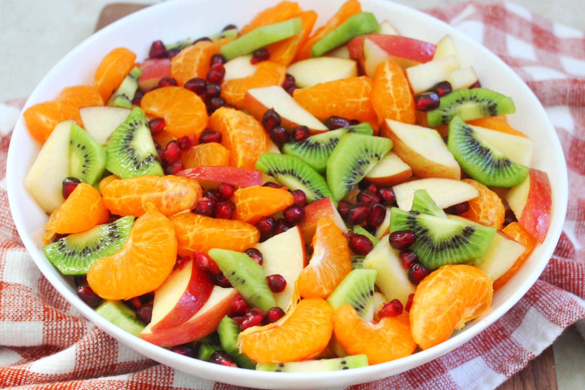 Winter fruit salad made with apples, pomegranate seeds, clementines, and kiwi. 