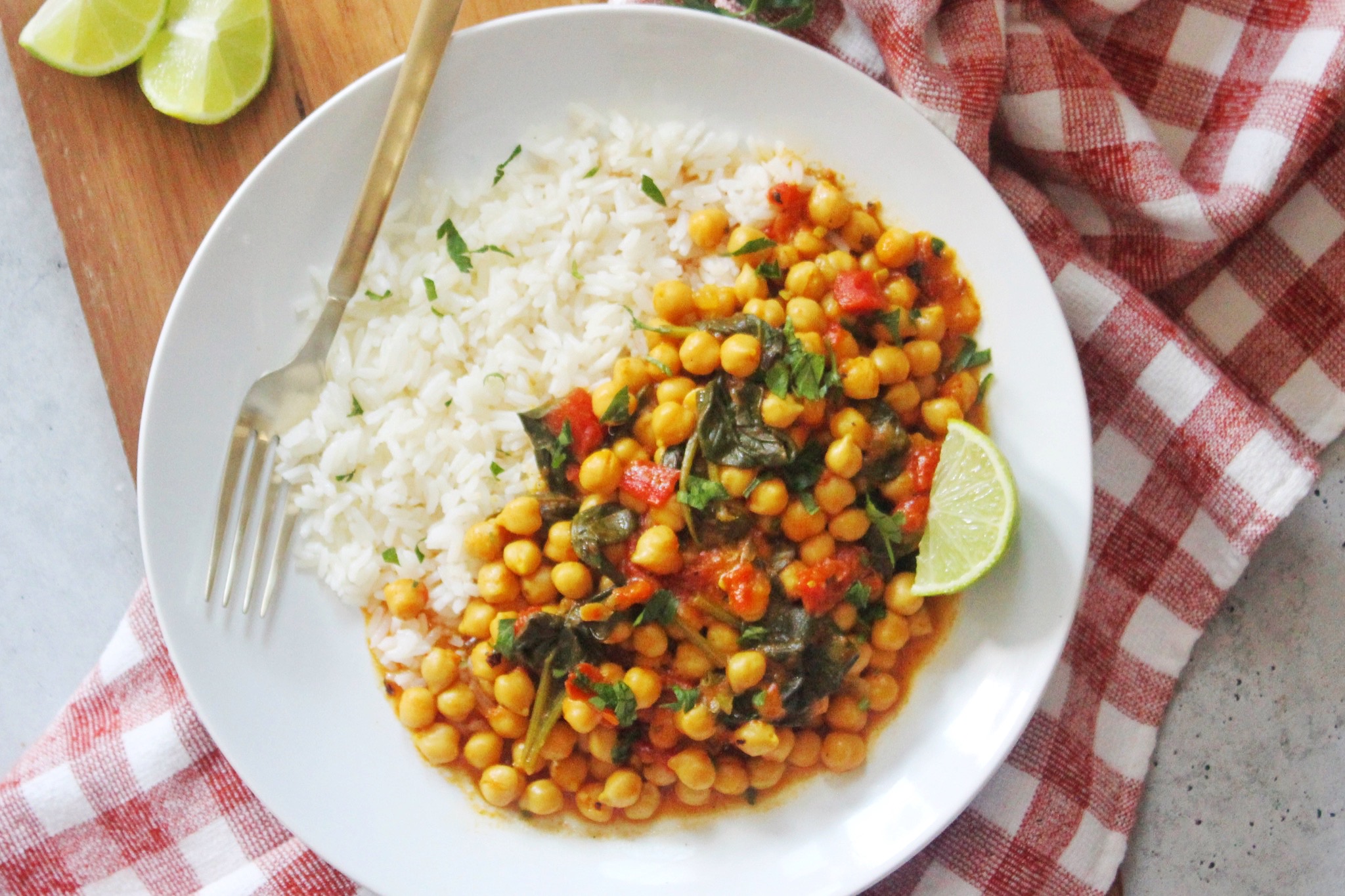 Chickpea curry served over white rice on a white plate. 